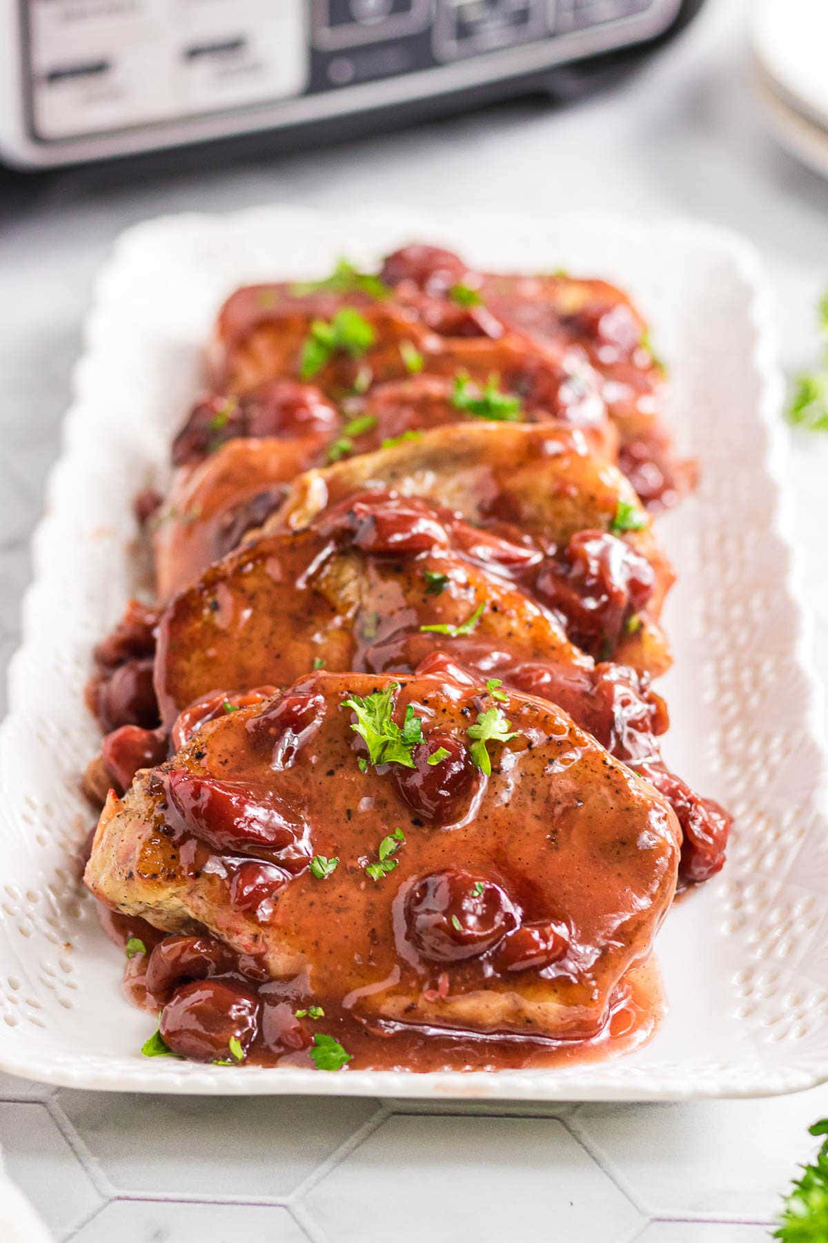 A platter with slow cooker cherry chipotle pork chops layered on each other.