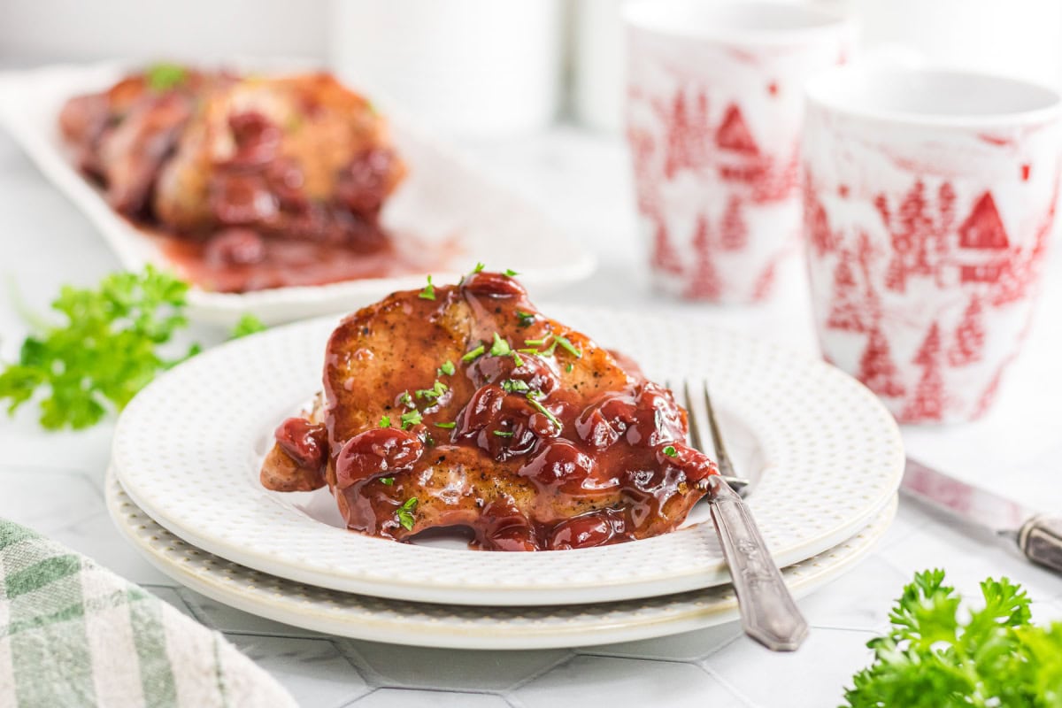 pork chops with a cherry sauce on a white plate.