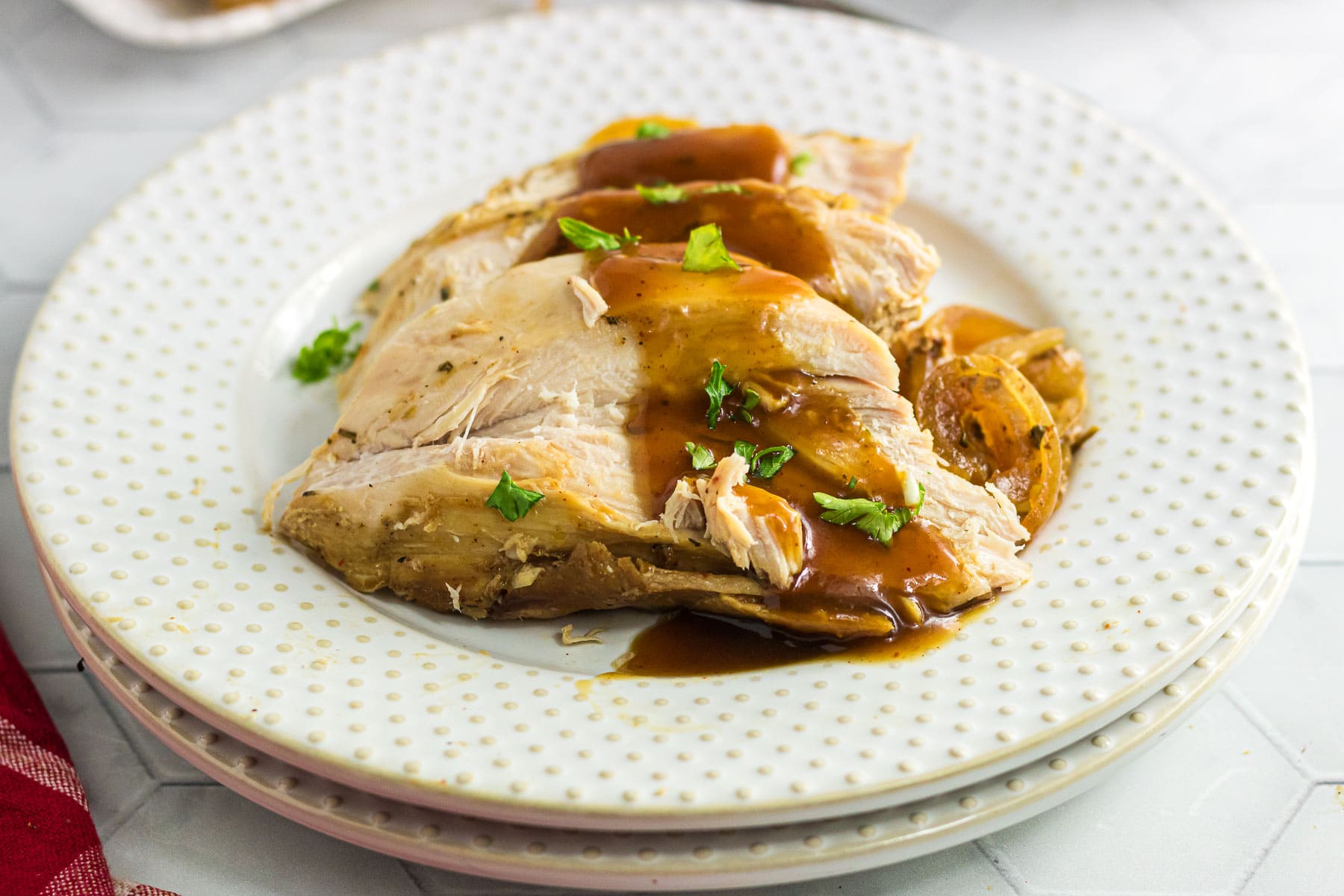 Closeup of slices of turkey breast covered in sauce on a white plate.