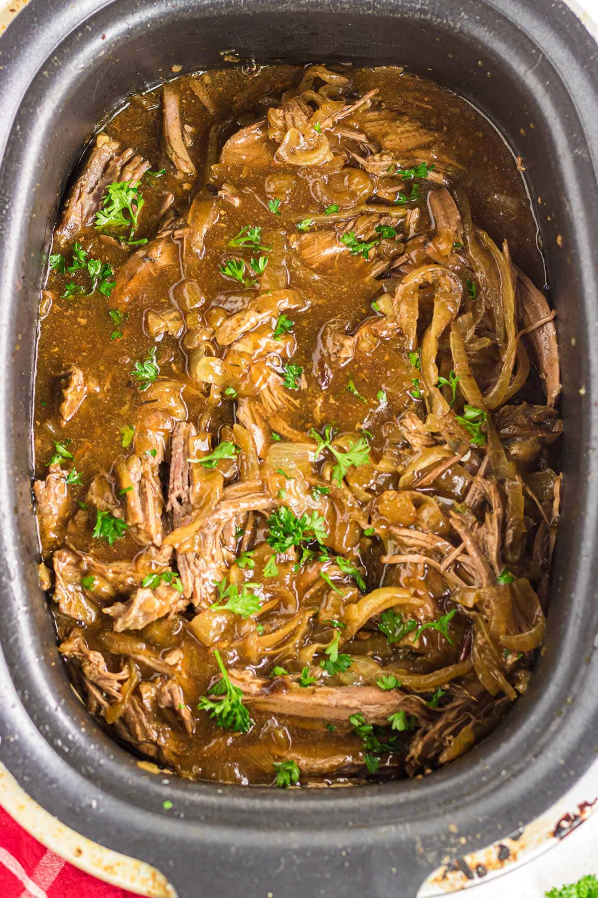 An overhead view of French onion pot roast in the slow cooker.