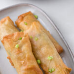 Golden brown spring rolls with a title text overlay for Pinterest.