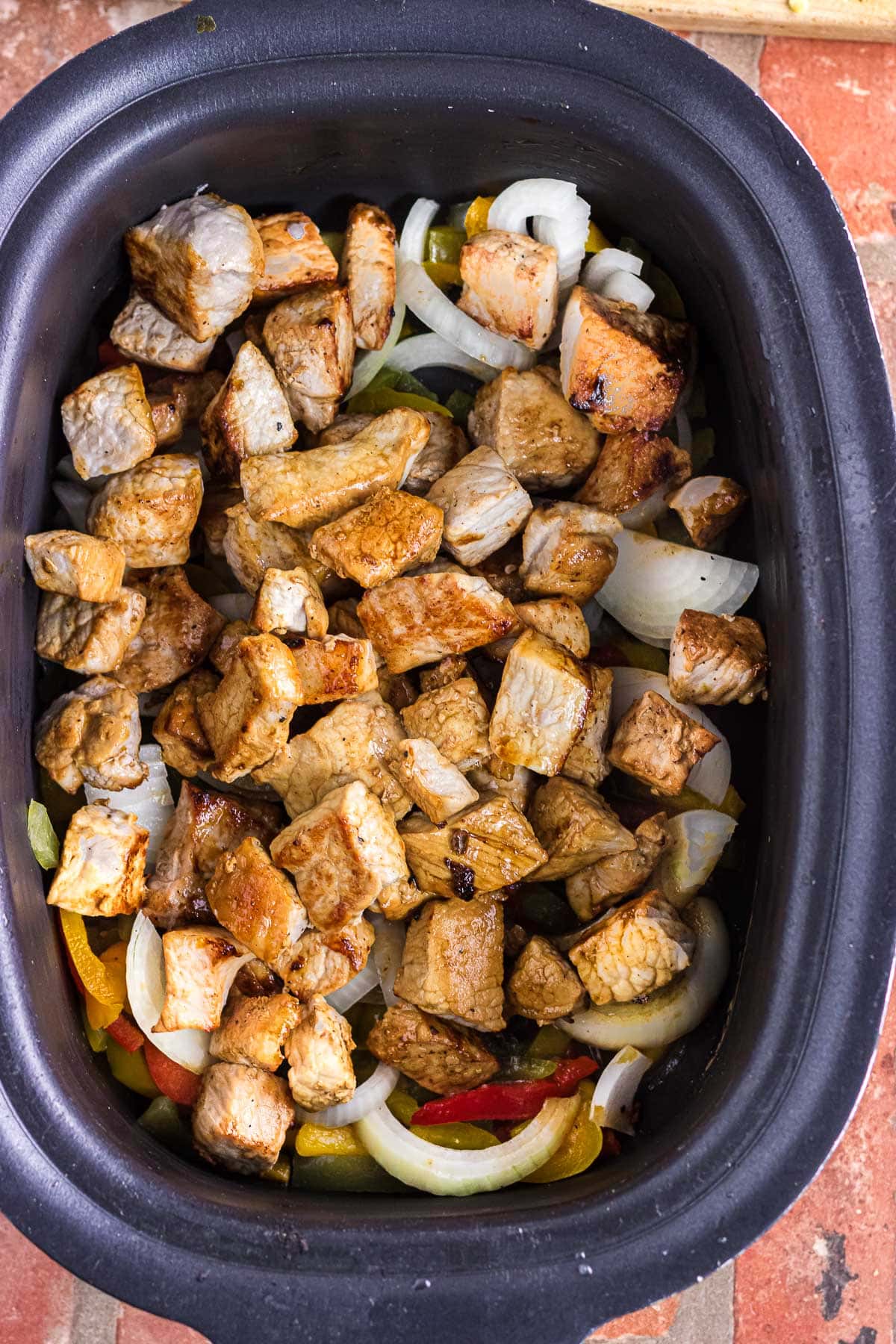 The seared pork chunks added to the slow cooker.