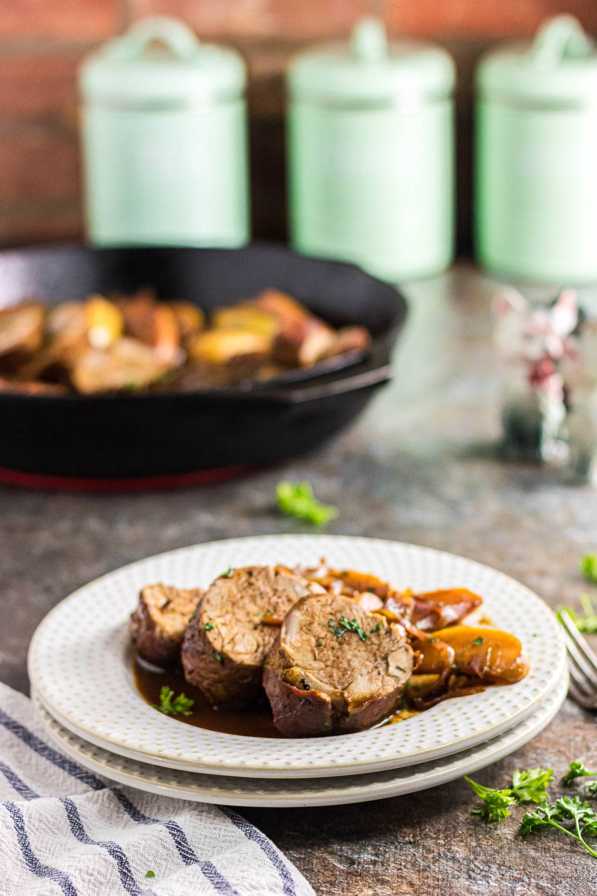 Three slices of pork tenderloin on a dinner plate with apples and onions.