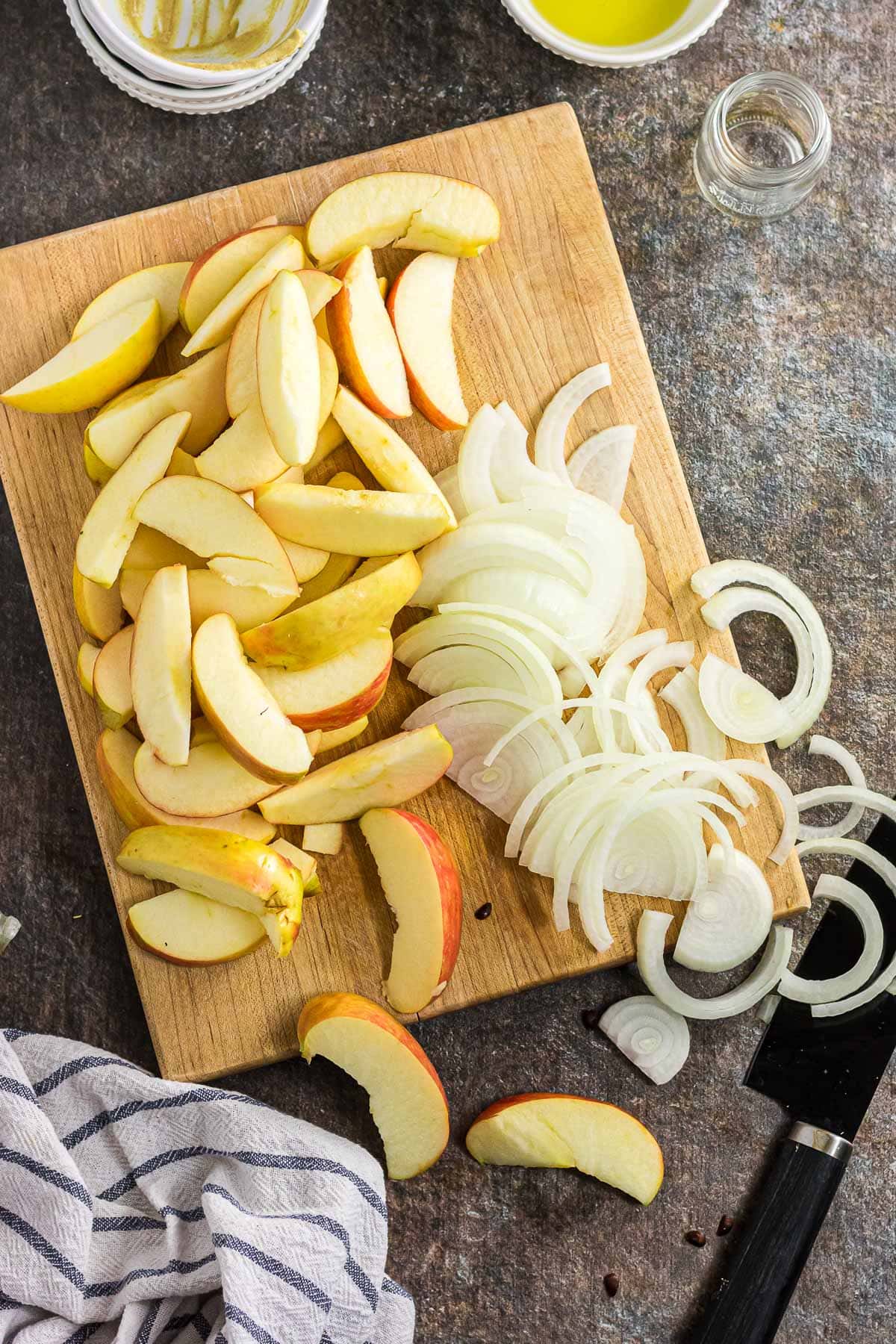 The apples and onions sliced on a cutting board.