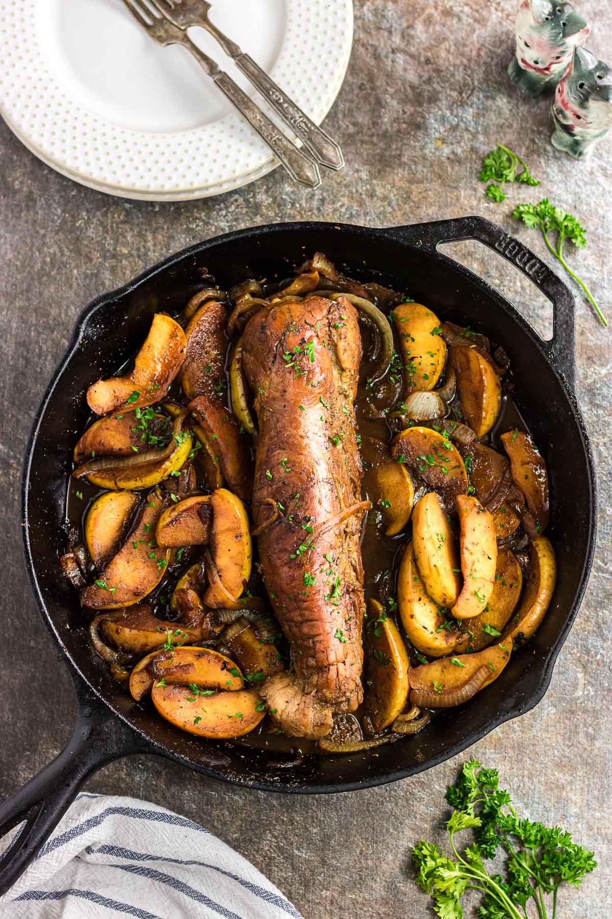 The pork tenderloin in a skillet with onions and apples.