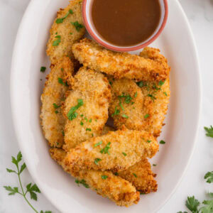 Overhead view of chicken tenders on a white plate for the feature image.