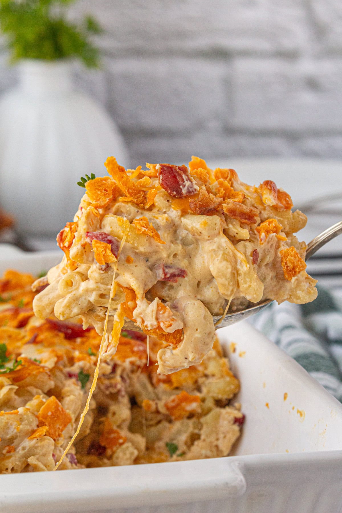 Scooping out a spoonful of bacon pimento mac and cheese from the baking dish.