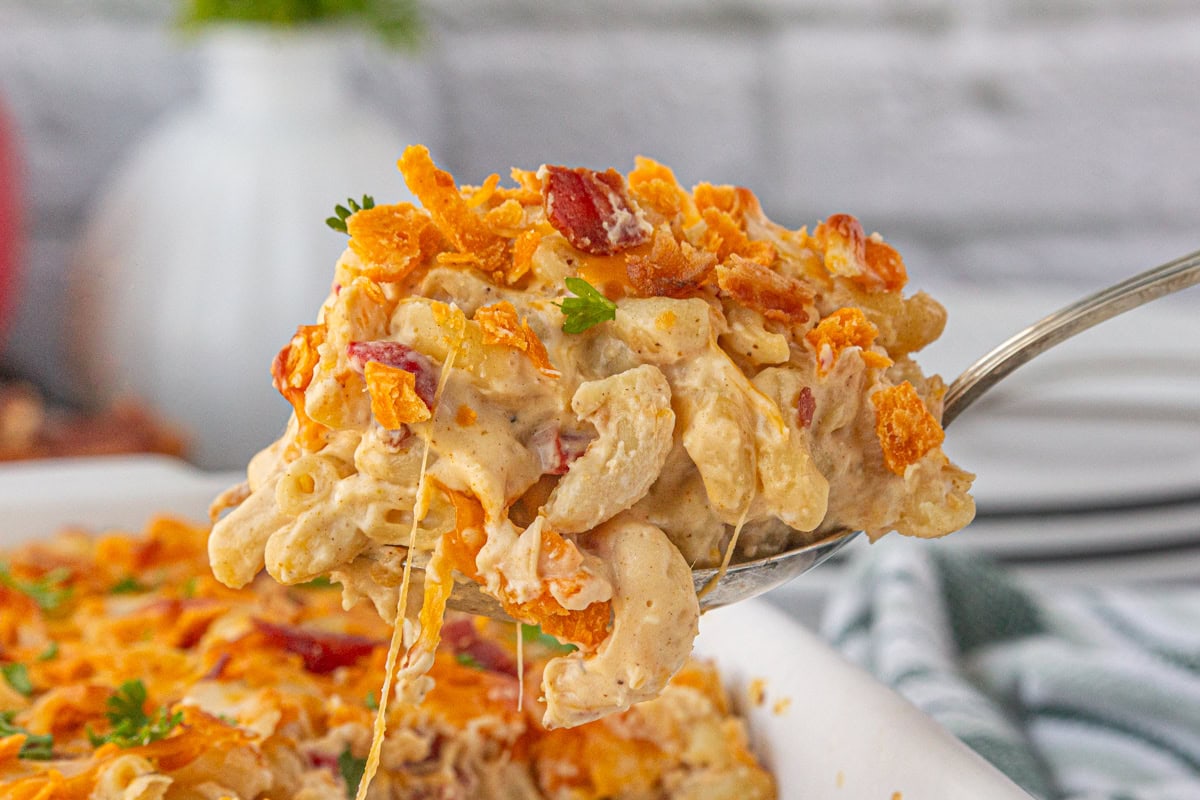 A serving of bacon pimento mac and cheese being lifted from the dish.