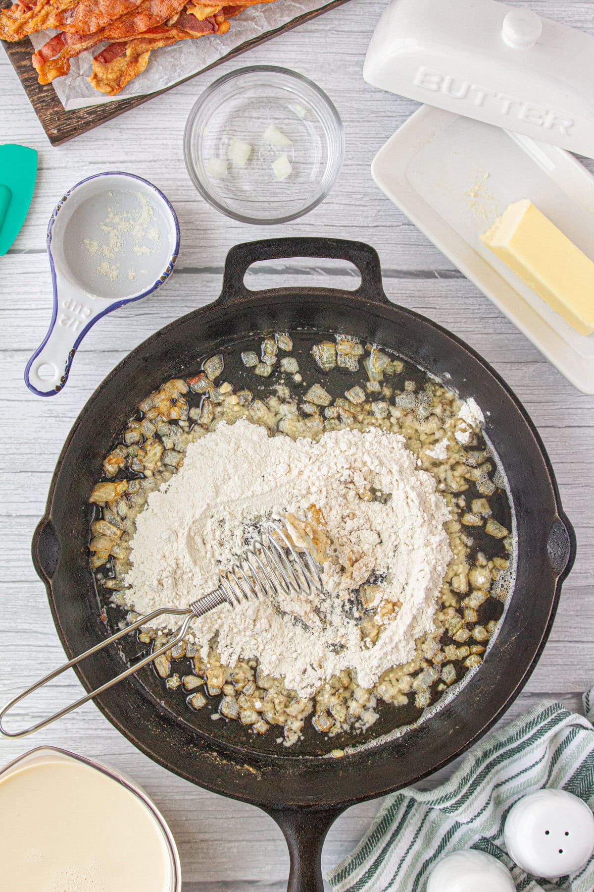 Whisking the flour in the onion, bacon grease, and butter mixture.