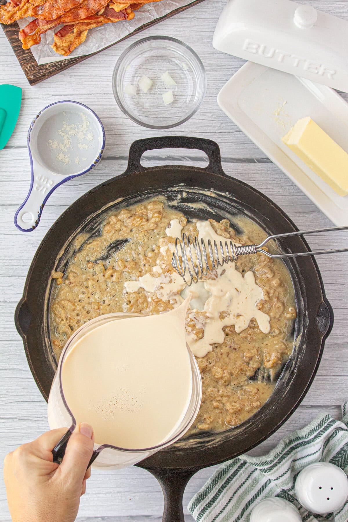 Pouring the evaporated milk into the roux of flour and onions.