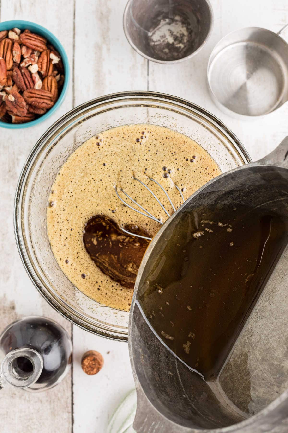 Brown butter mixture being poured into egg mixture.