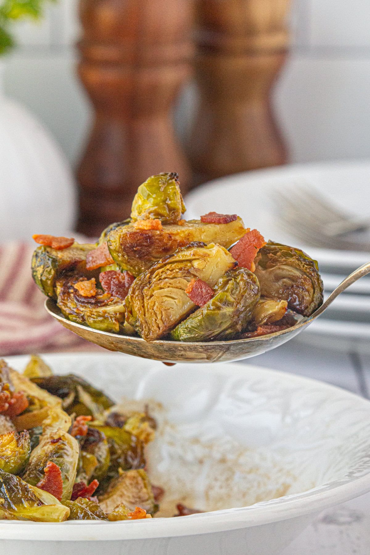 An up-close view of Brussels sprouts with hot bacon dressing on a serving spoon.