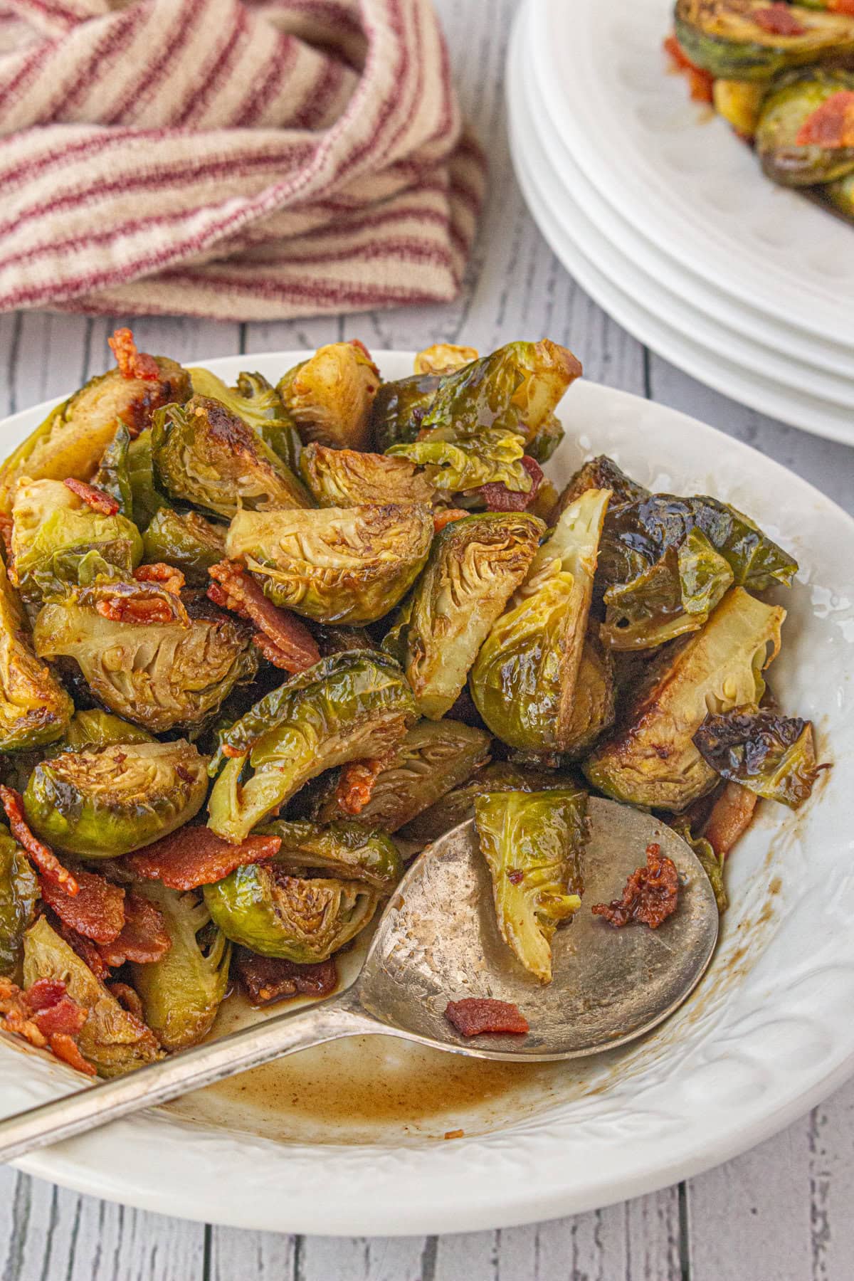 Brussels sprouts with hot bacon dressing in a serving bowl with a serving spoon. 