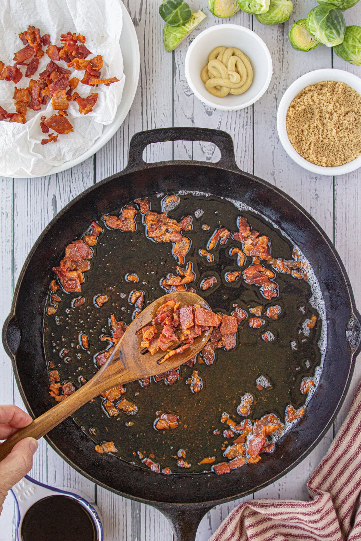 Scooping out the cooked bacon from the skillet with a slotted spoon.