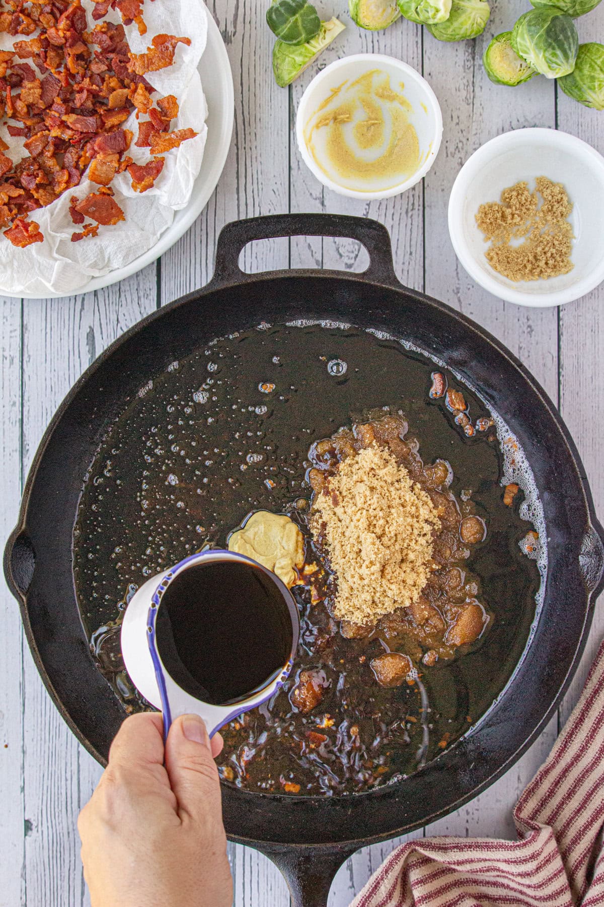 Adding the dressing ingredients to the bacon drippings in the skillet.