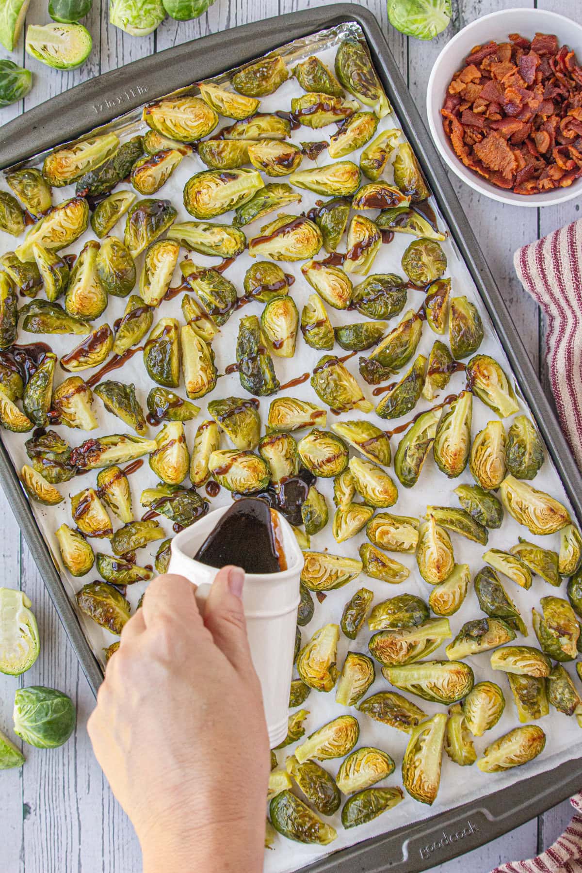 Pouring the hot bacon dressing over the roasted Brussels sprouts.