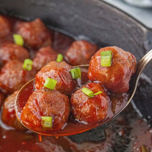 Cranberry sauce meatballs in an iron skillet.