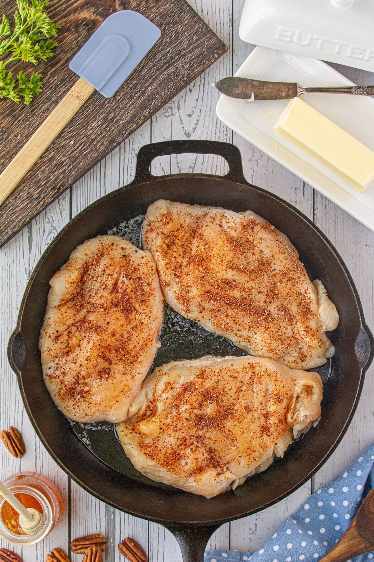 Seasoned chicken breasts searing in the skillet.