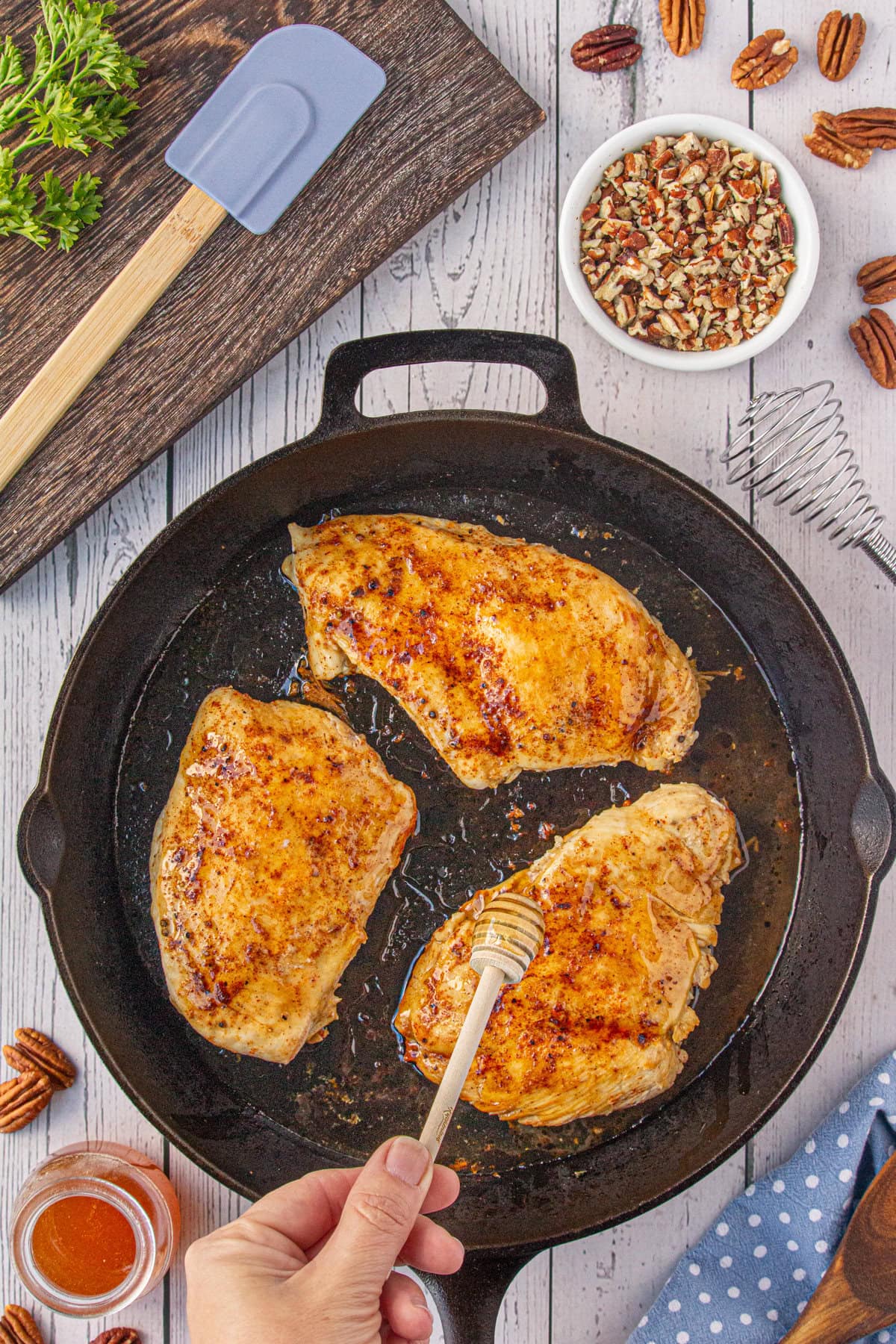 Drizzling the cooked chicken breasts with honey.