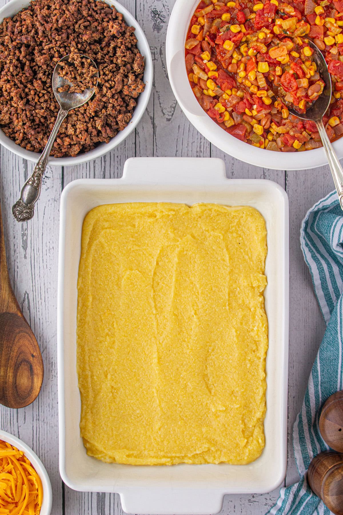 The bottom of the casserole dish covered with half the cooked cornmeal mixture.