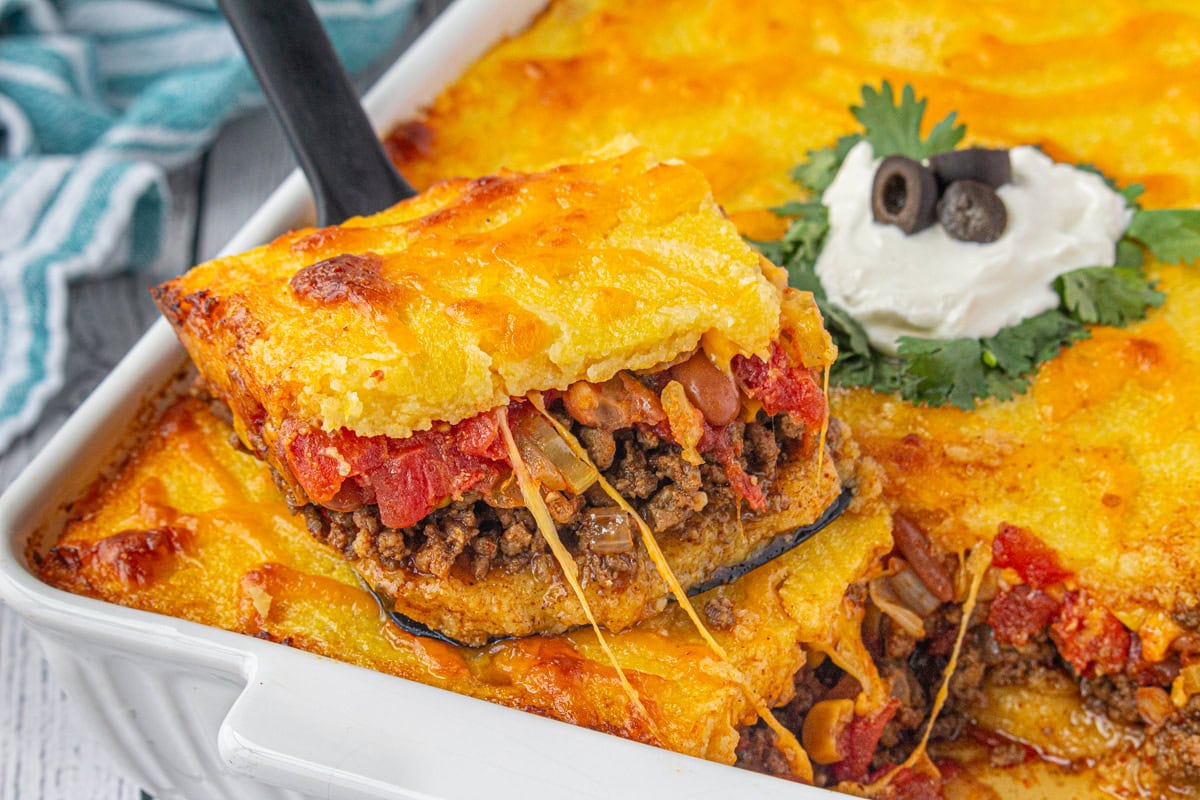 A serving of tamale pie being lifted from the casserole dish.