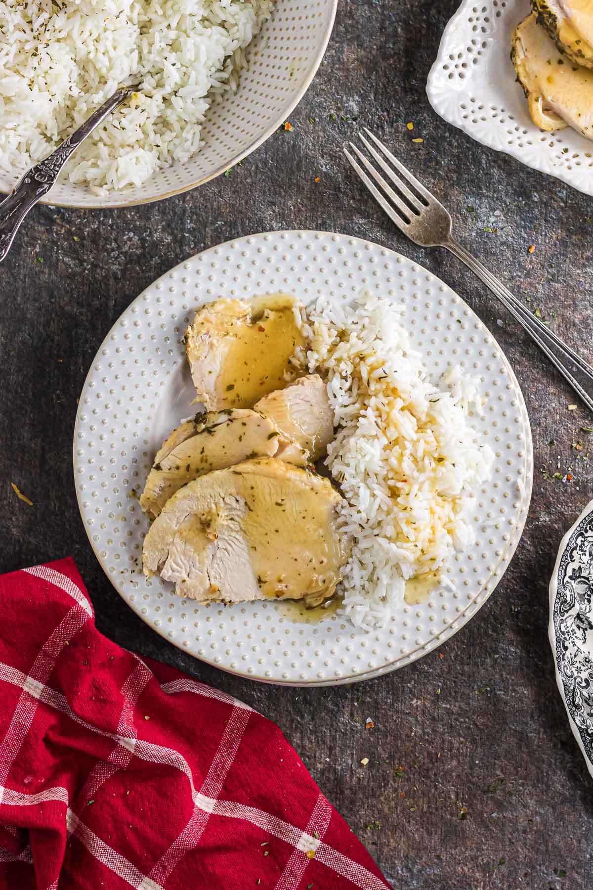 An overhead view of sliced boneless turkey breast on a plate with rice and gravy.