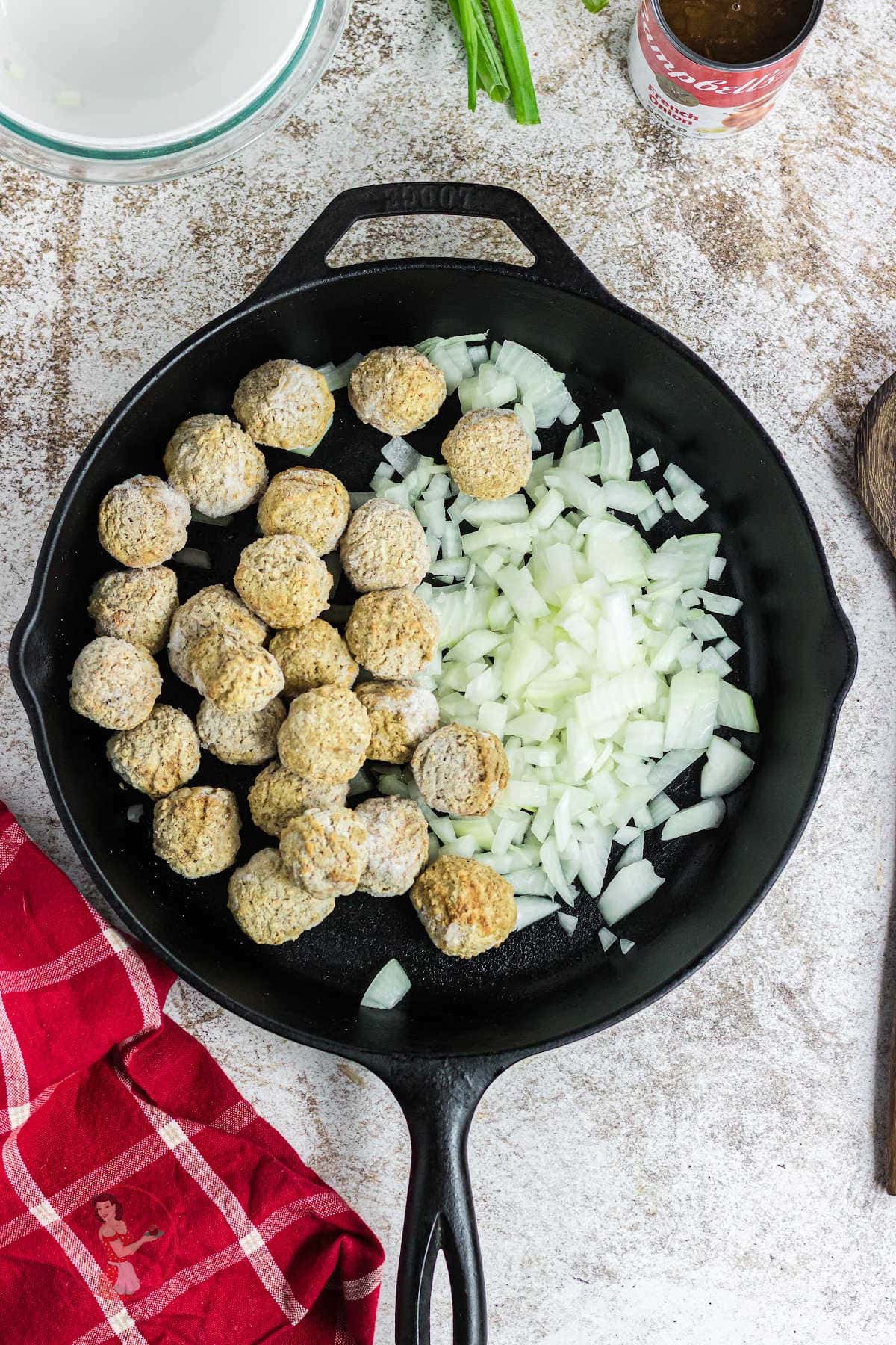 Frozen meatballs and onions in a skillet.