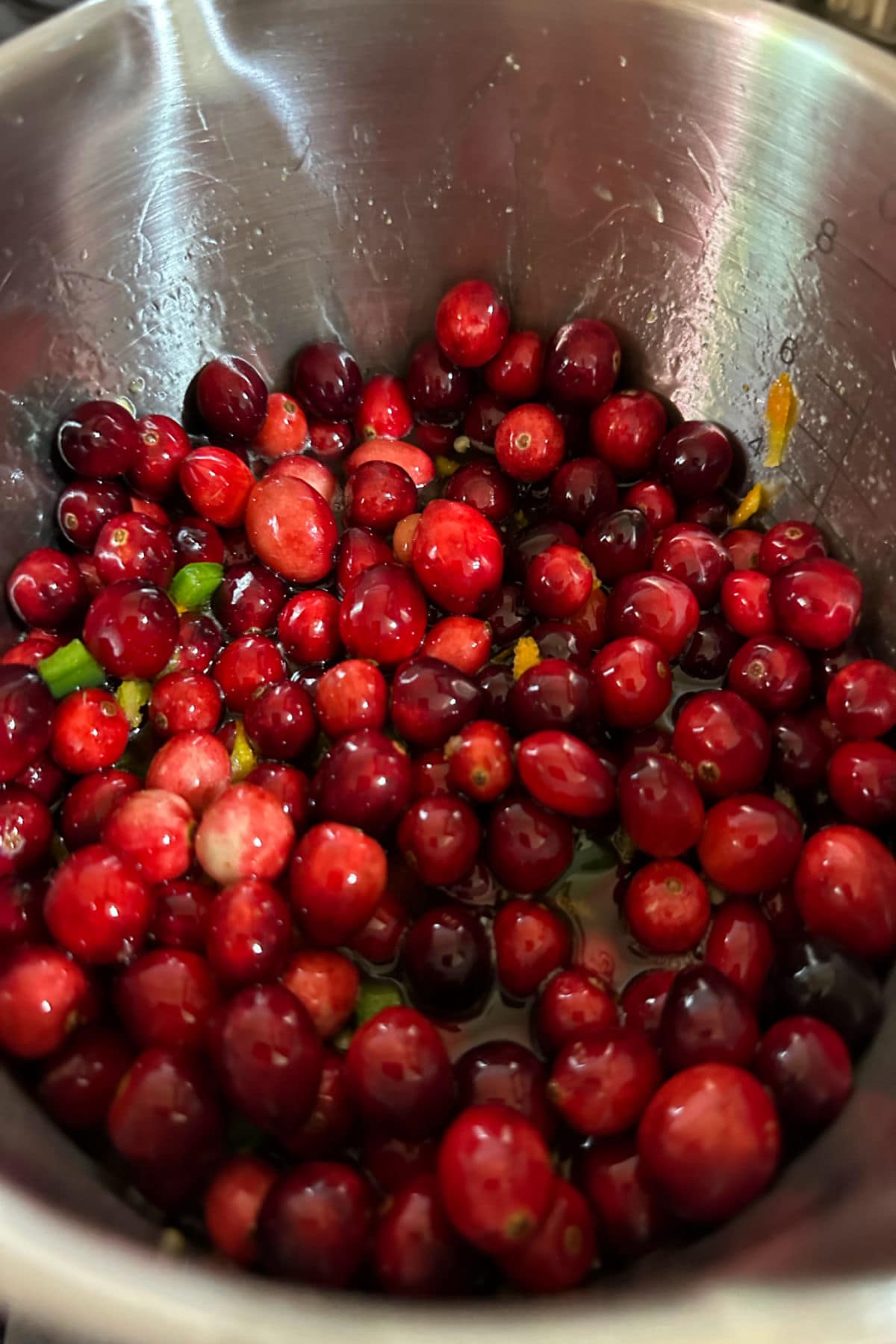 Adding the whole cranberries to the other simmering ingredients.