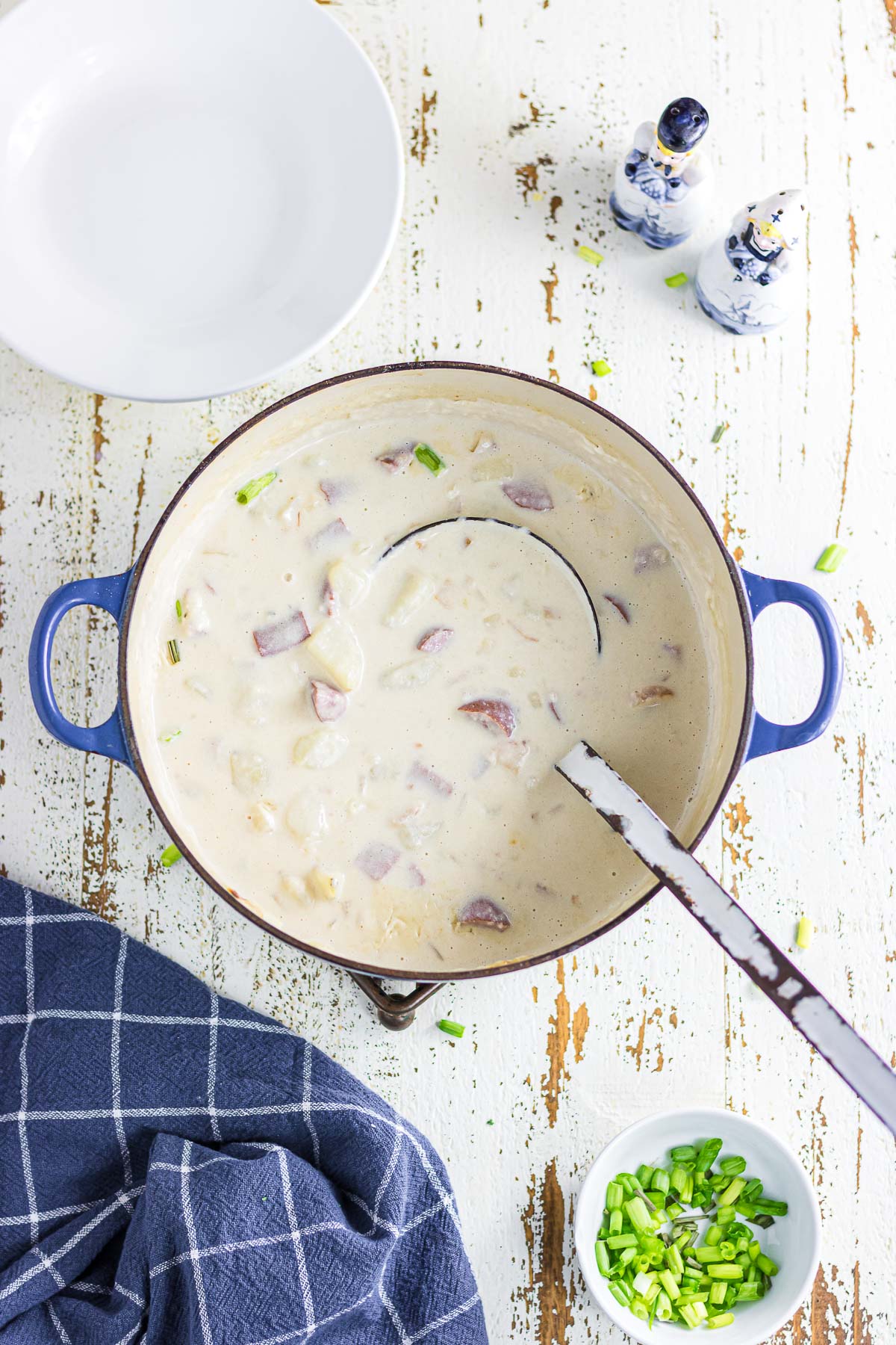 An overhead photo of smoked sausage potato soup in a Dutch oven with a serving spoon.