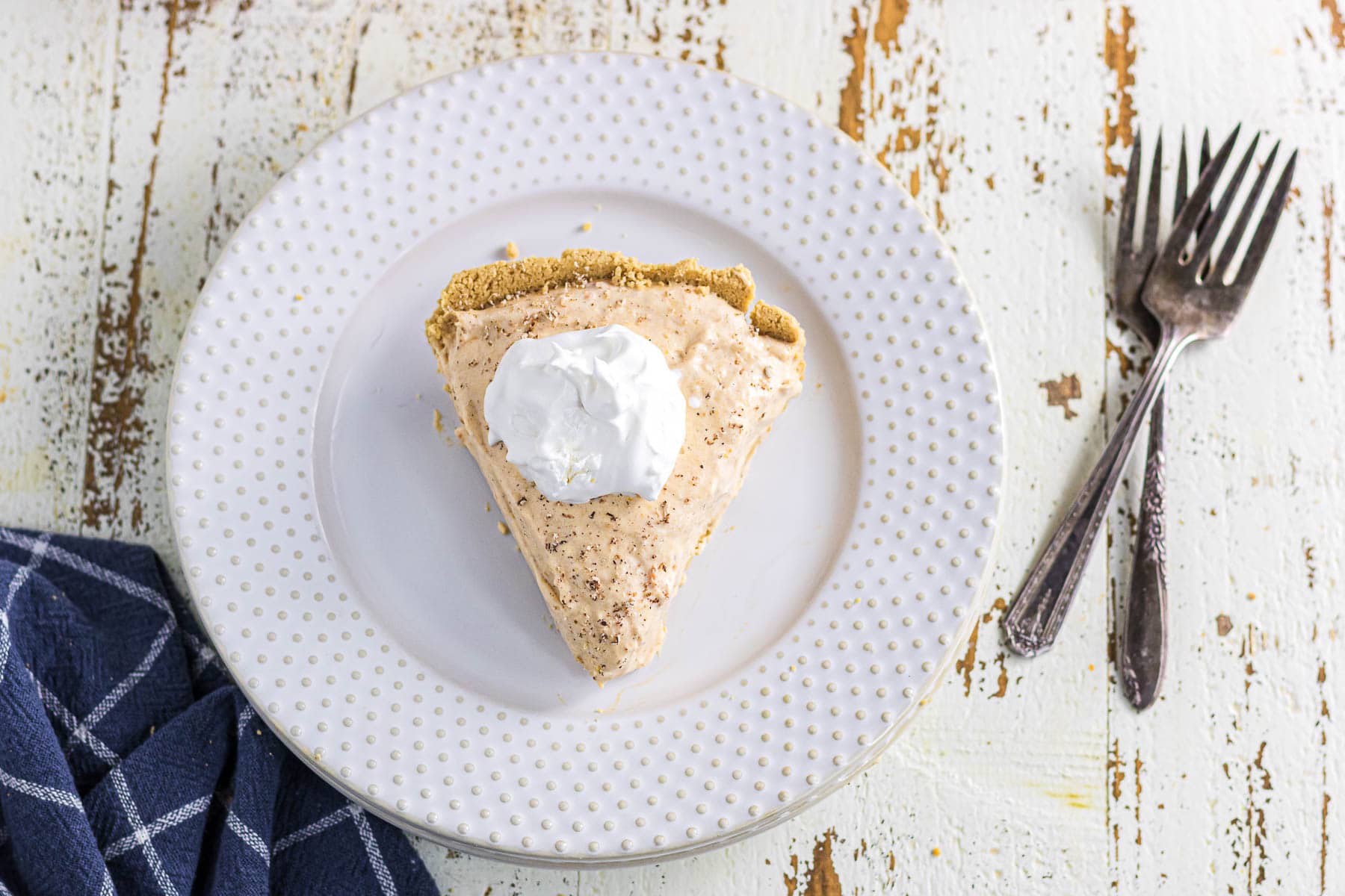 Overhead view of a slice of sweet potato pie with Cool Whip on top.