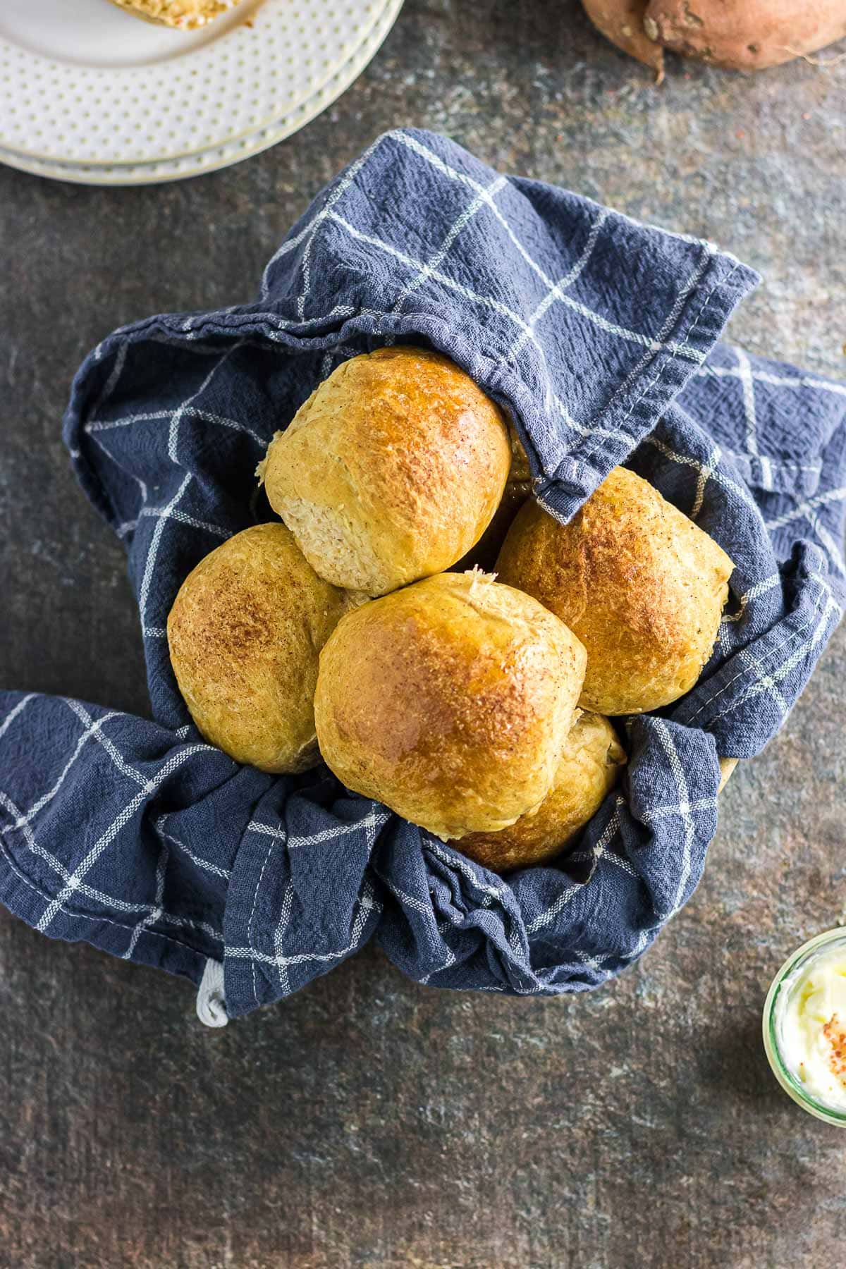 Sweet potato dinner rolls topped with honey cinnamon glaze in a bread basket.