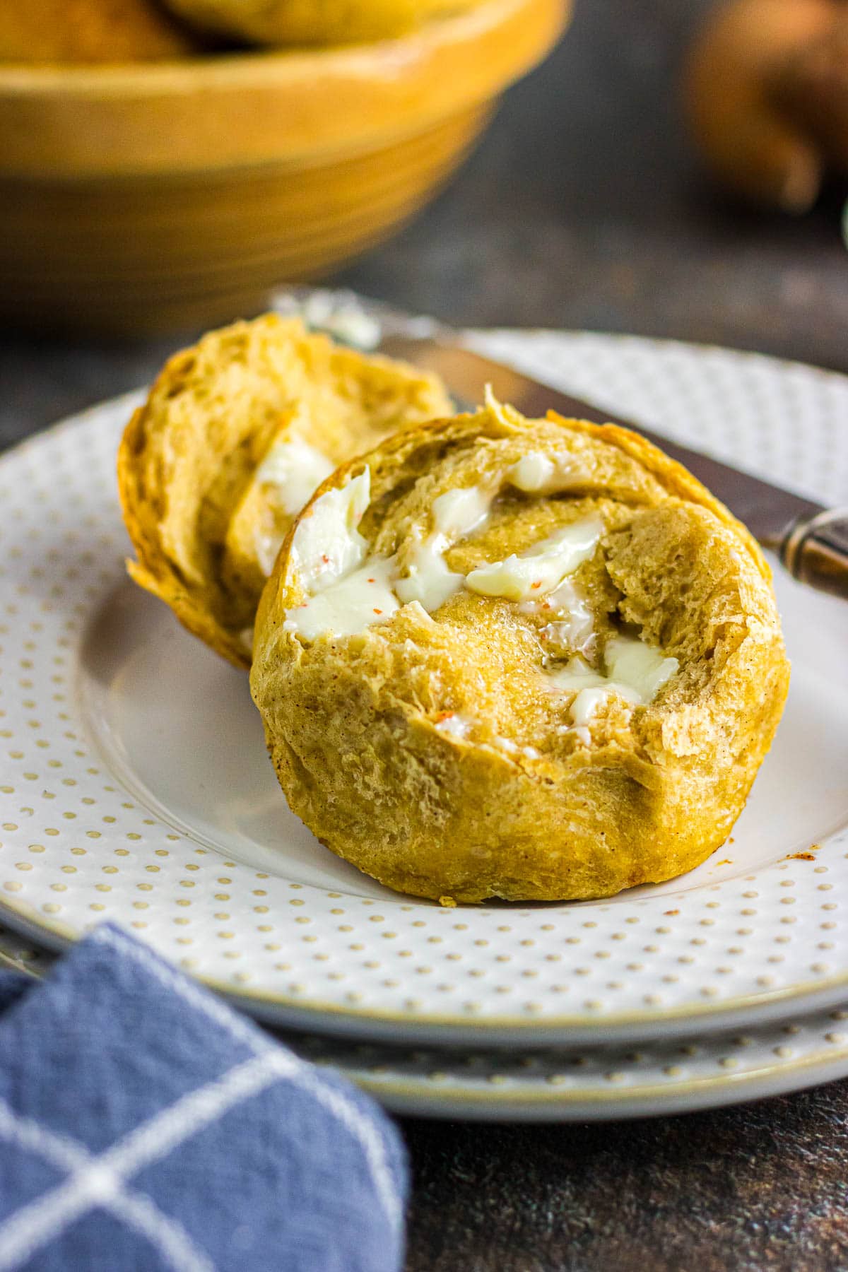 A sweet potato dinner roll split in half and smeared with melted butter.