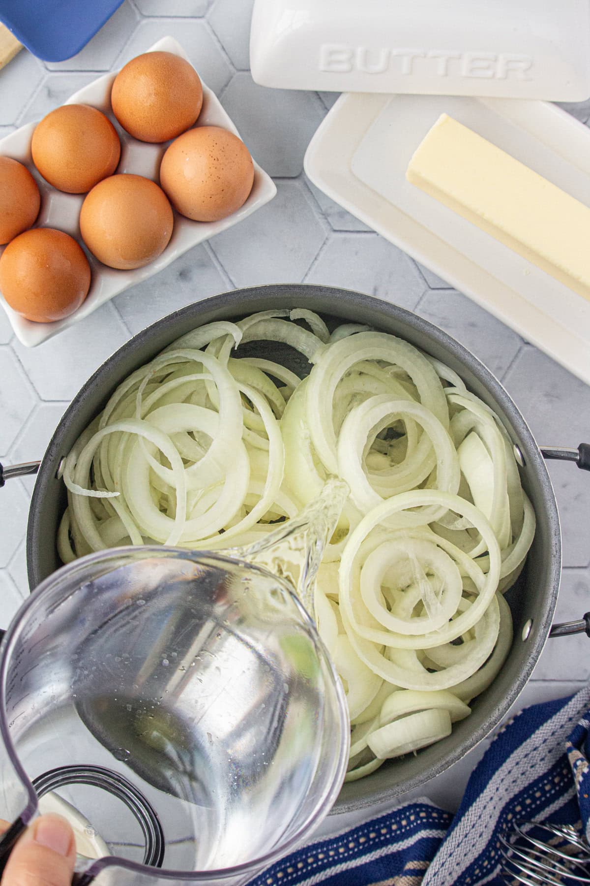 Adding water to the onions in a pan.