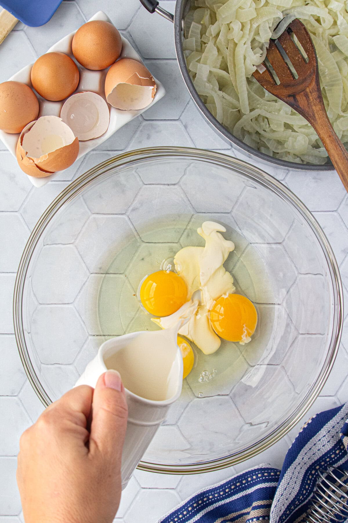 Combining eggs and evaporated milk in a mixing bowl.