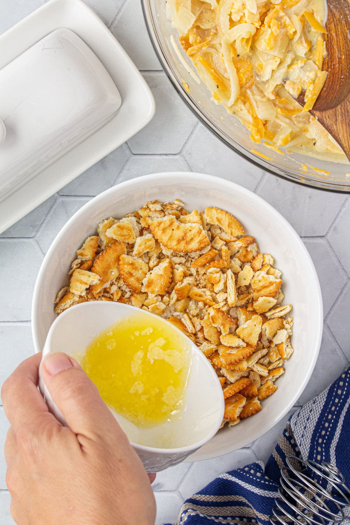 Adding butter to the crushed crackers in a small bowl.