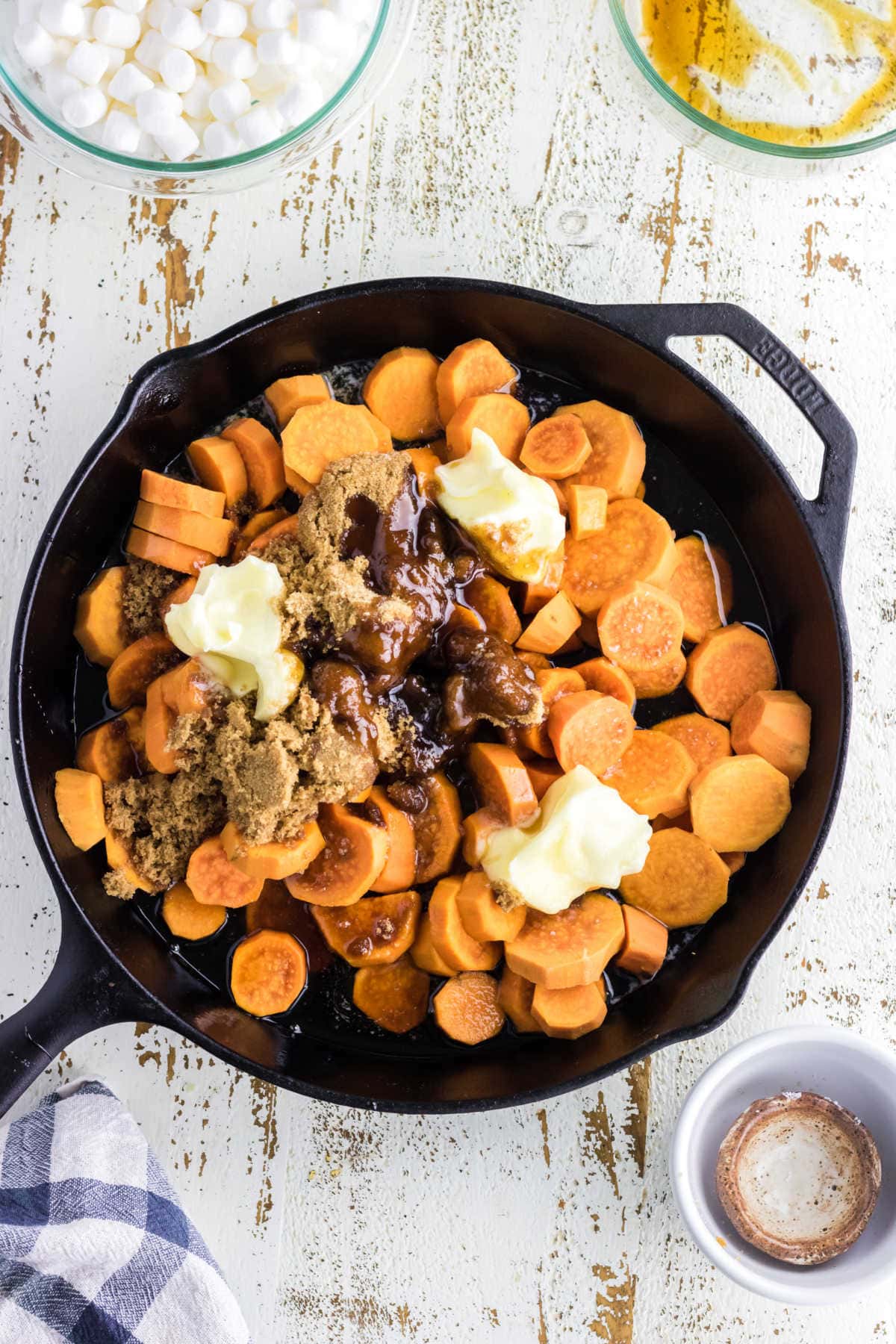 Drained sweet potatoes in a skillet with butter and remaining ingredients.