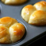 Closeup of cloverleaf rolls in a muffin tin.