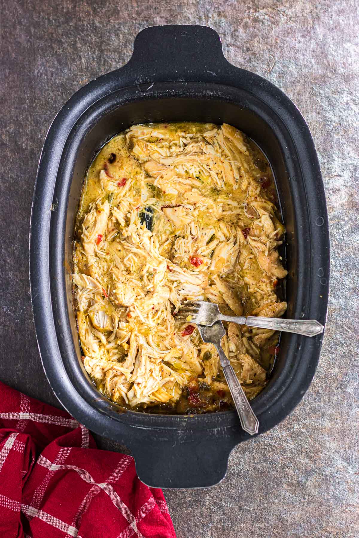 Shredding the cooked chicken in the slow cooker.