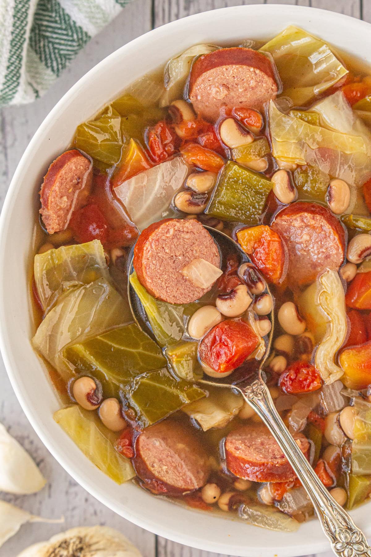 An overhead view of sausage, black eyed pea, and cabbage soup in a dinner bowl.