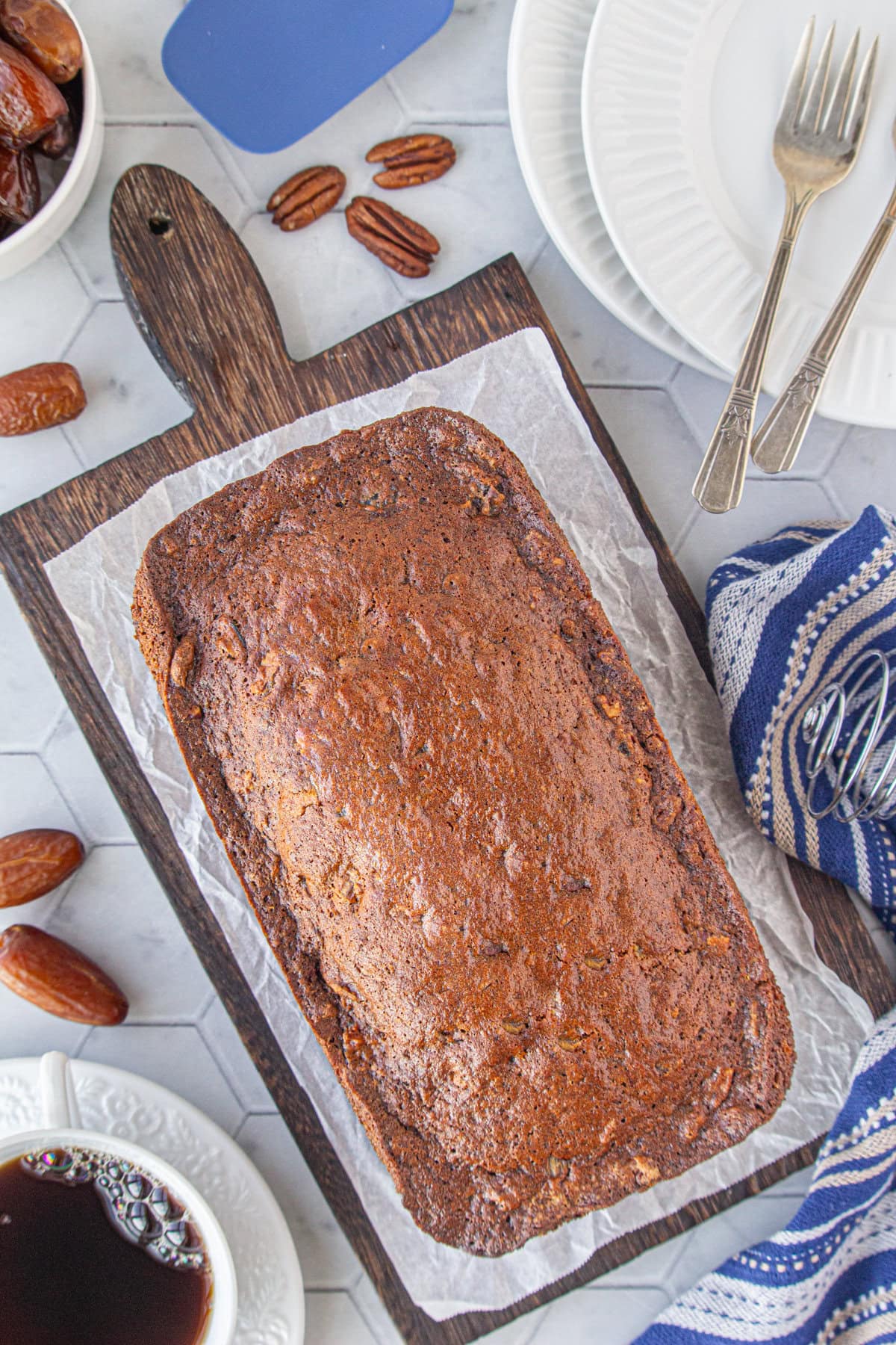 An overhead view of unsliced date nut bread on a serving board.