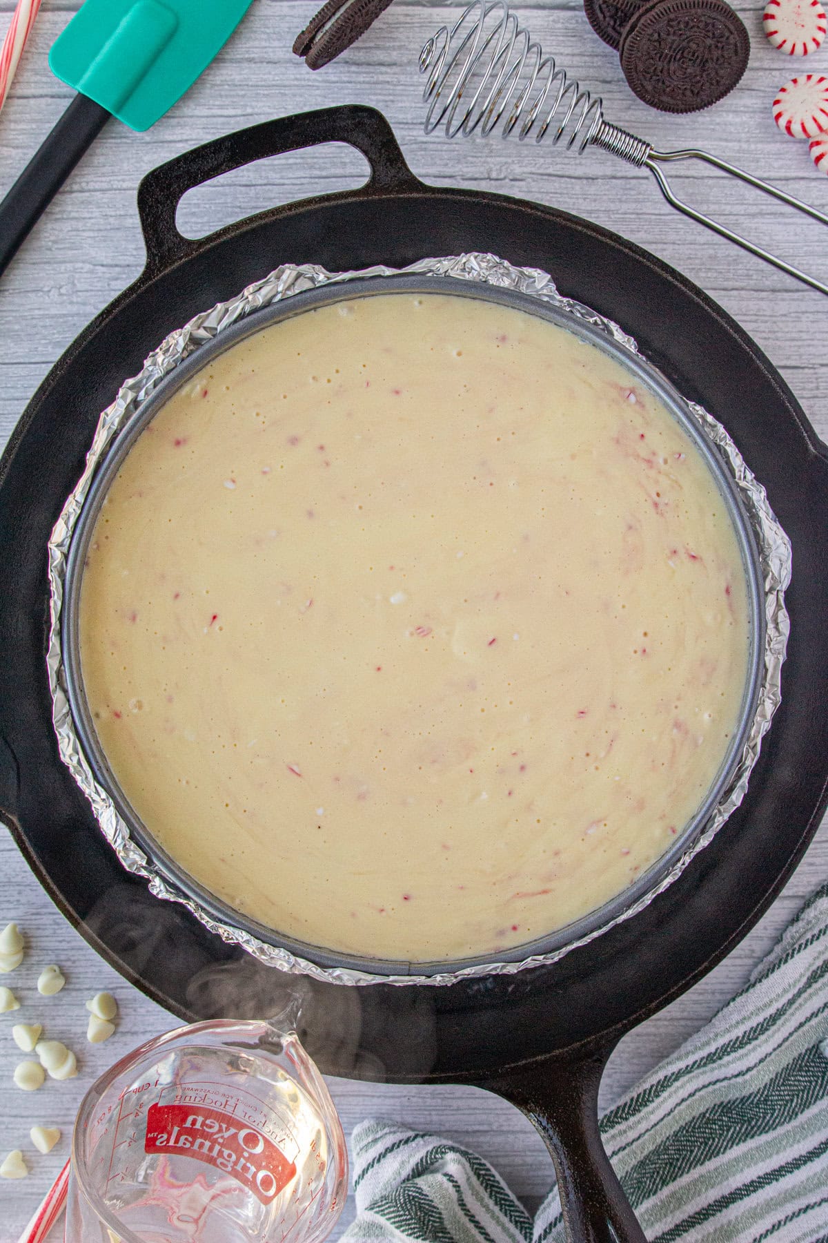 Cheesecake pan, covered in foil, is placed in a water bath.