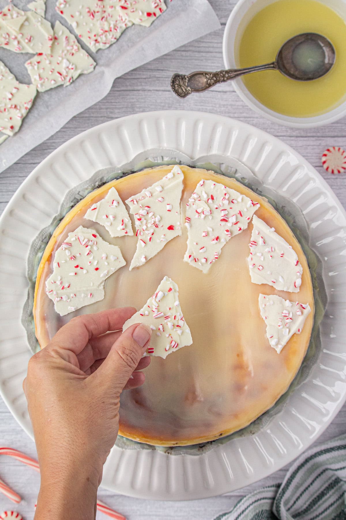 Peppermint bark is arranged on the finished cheesecake as a garnish.