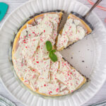 Overhead view of peppermint bark cheesecake on a white plate.