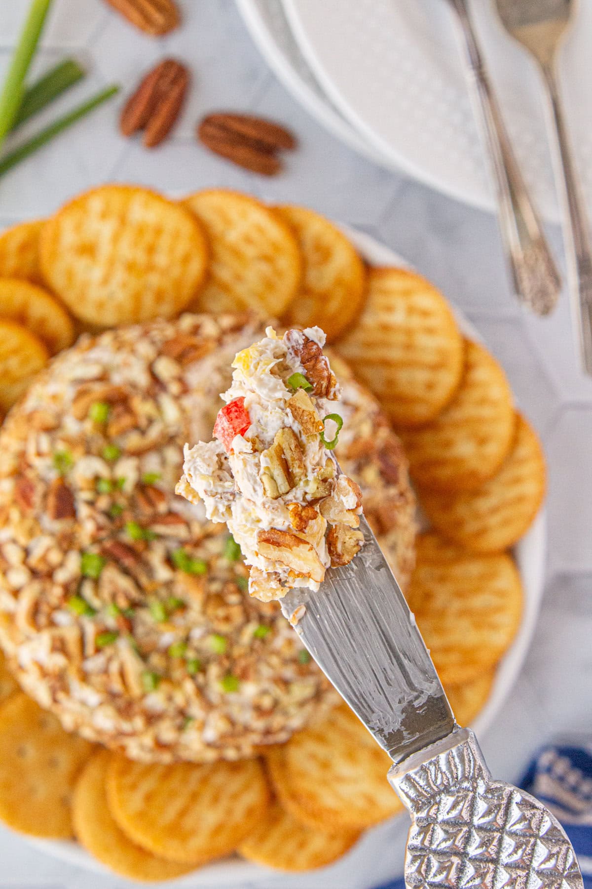 An up-close view of a scoop of pineapple cheese ball on a knife.