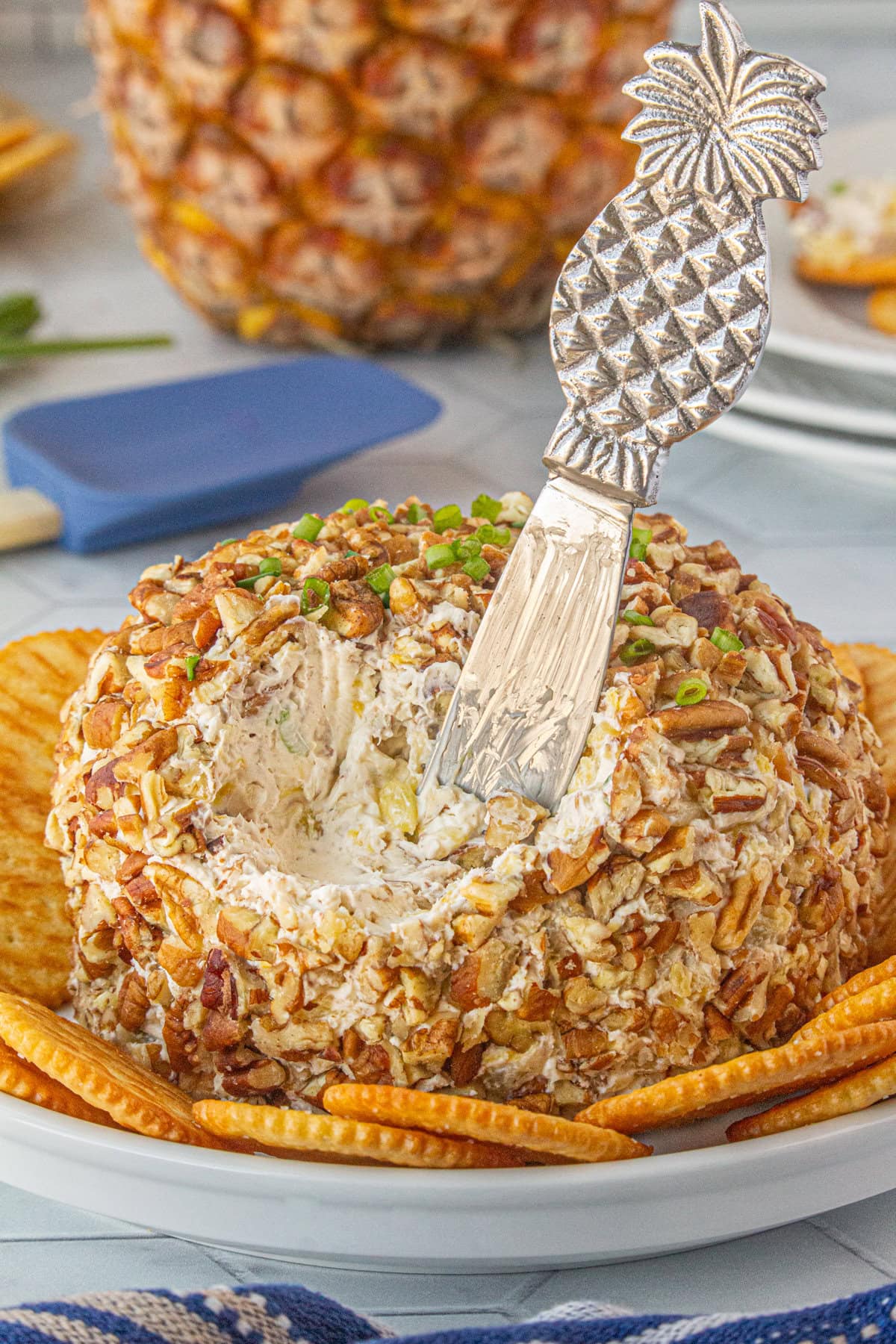 A serving knife scooping into the pineapple cheese ball.