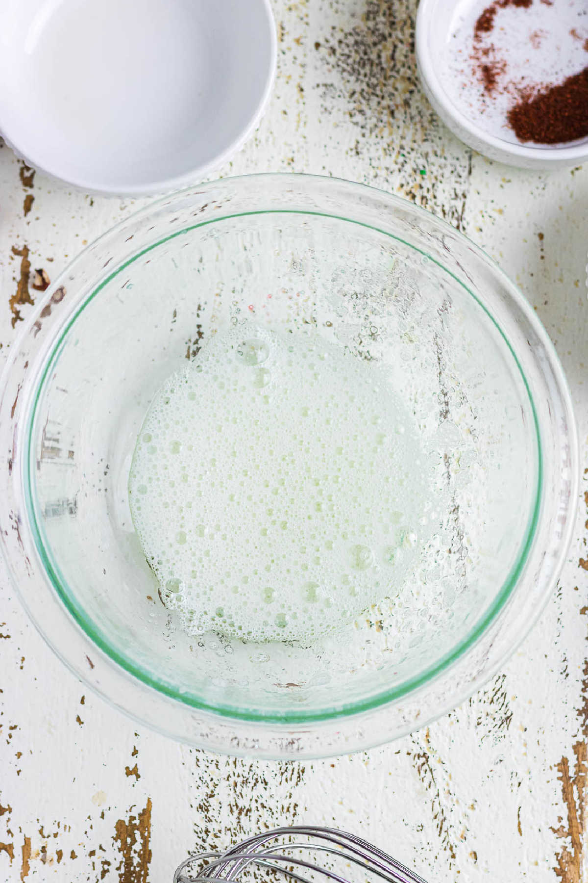 Frothy egg whites in a glass bowl.