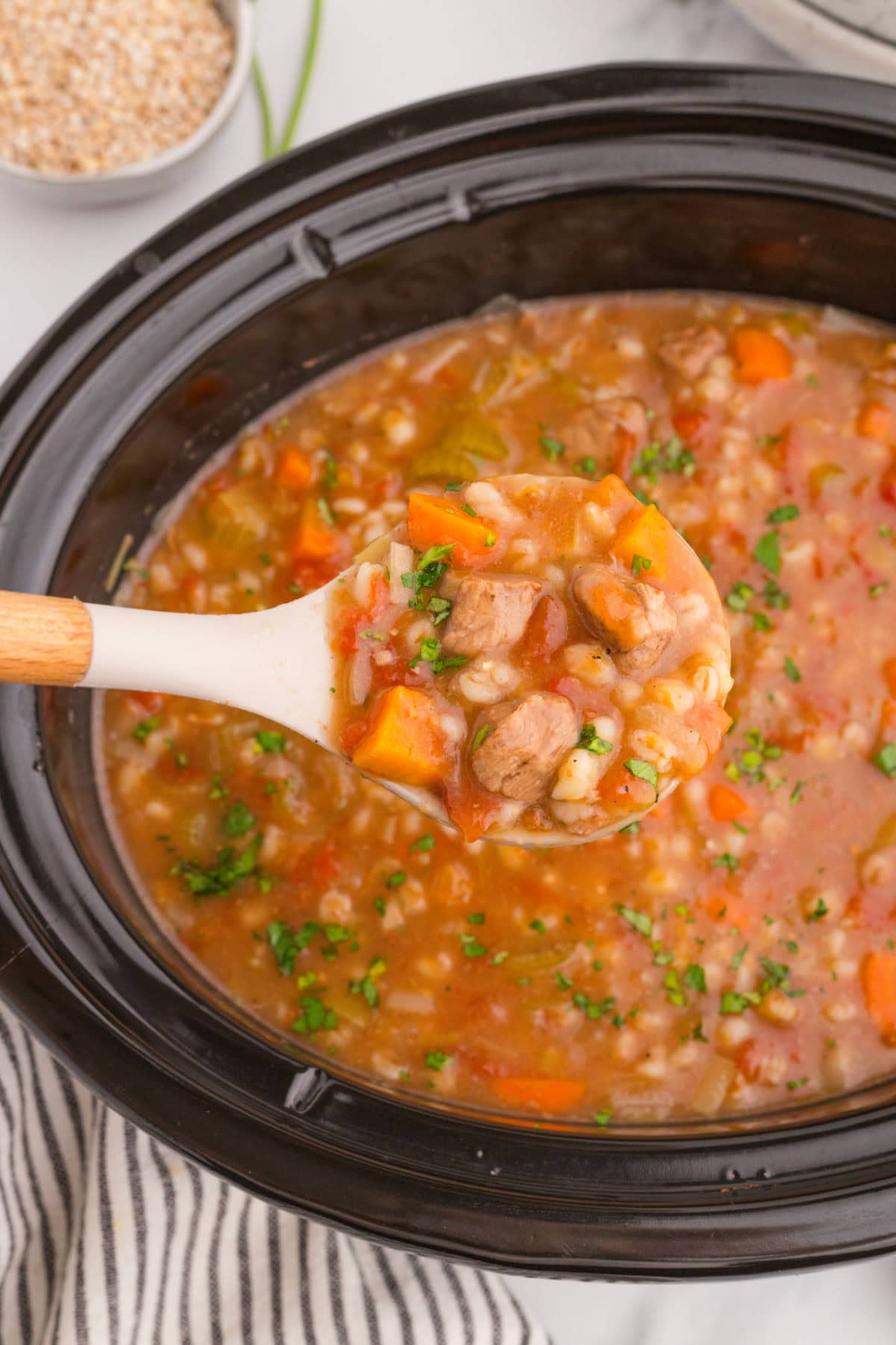 A ladle full of soup being removed from the crockpot.