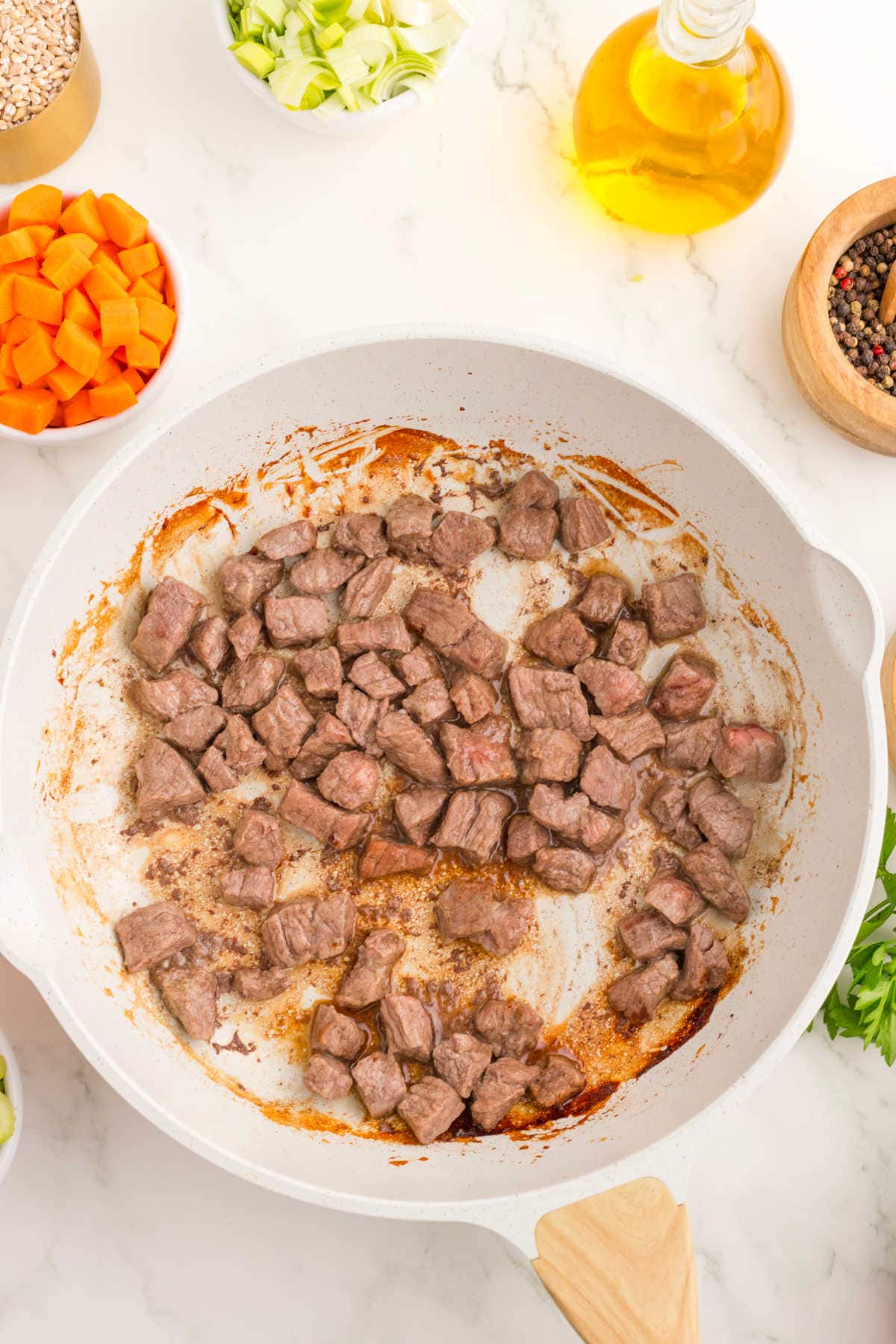 Browned beef cubes in a frying pan.