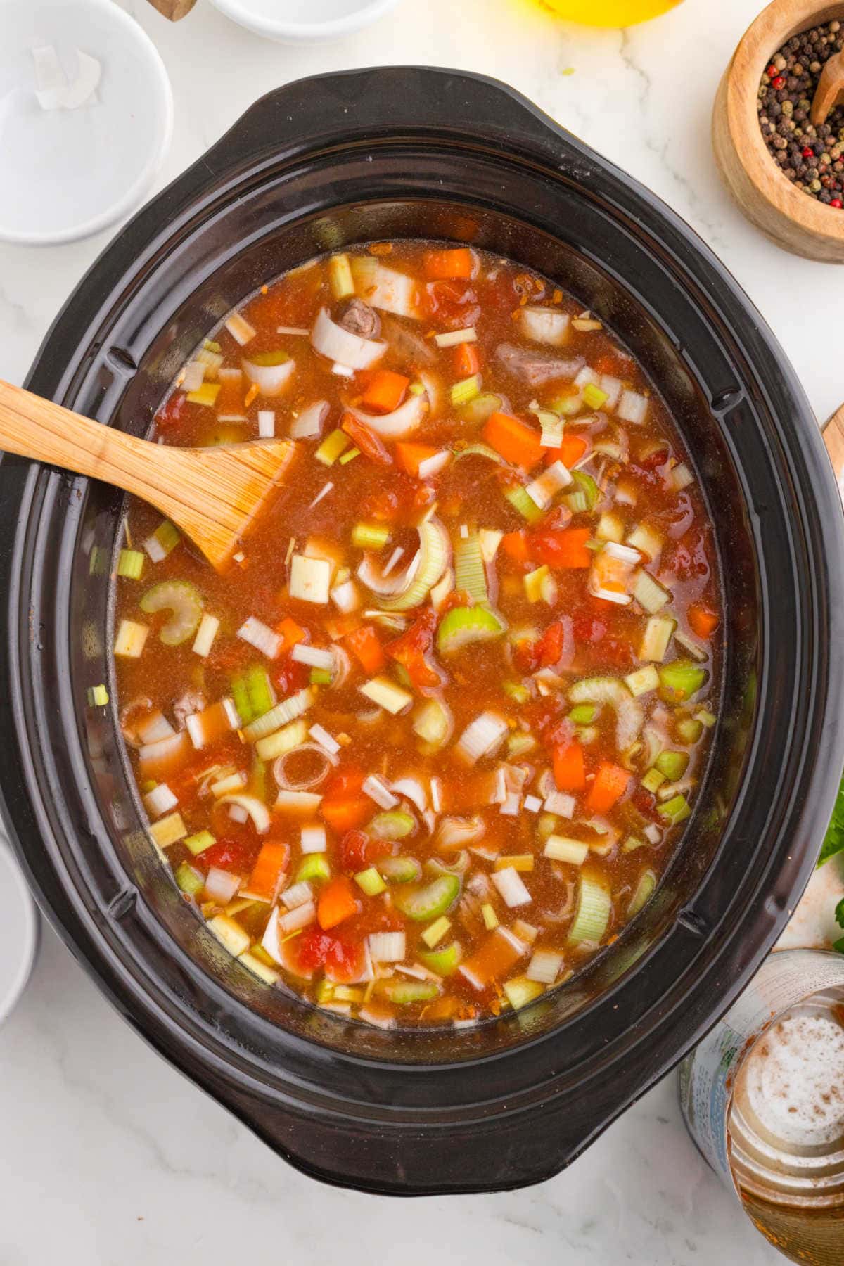 Ingredients in slow cooker being stirred.