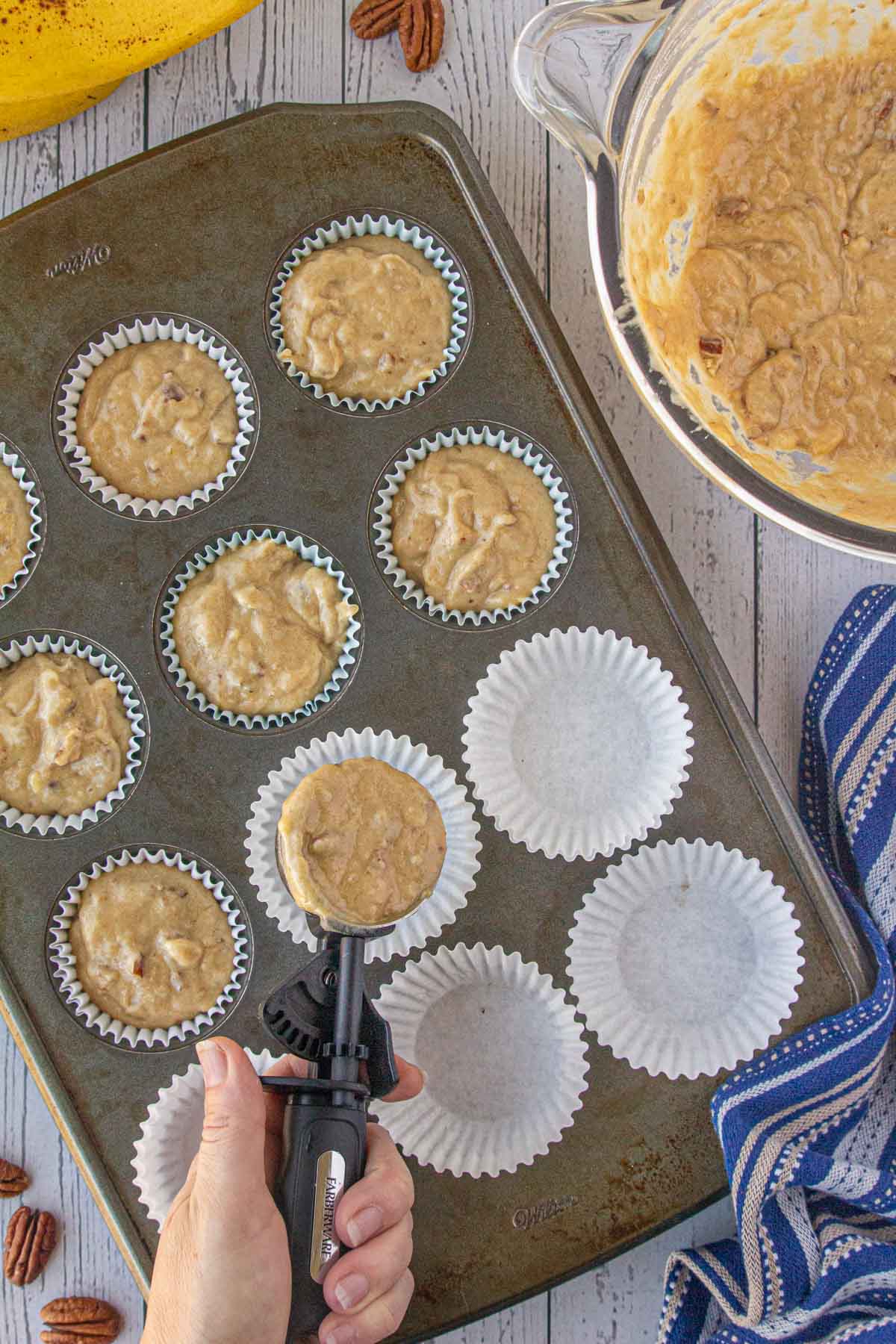 Portioning the brown butter banana pecan muffin batter into a muffin tin.